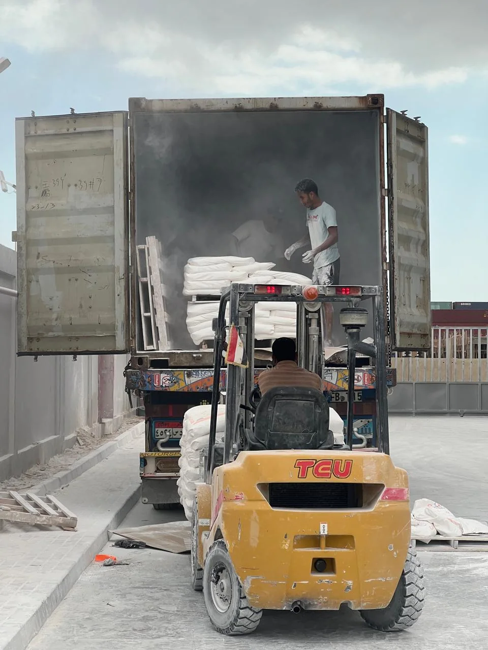 Forklift loading palletised mineral bags into a container